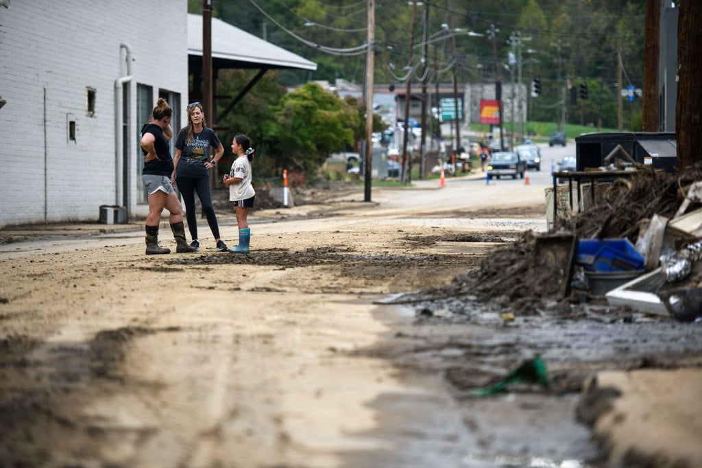Neighbors speak together downtown while working to remove damaged items and salvage others on Oct. 4 in Canton, North Carolina. (Melissa Sue Gerrits/Getty Images/The 19th/2024)