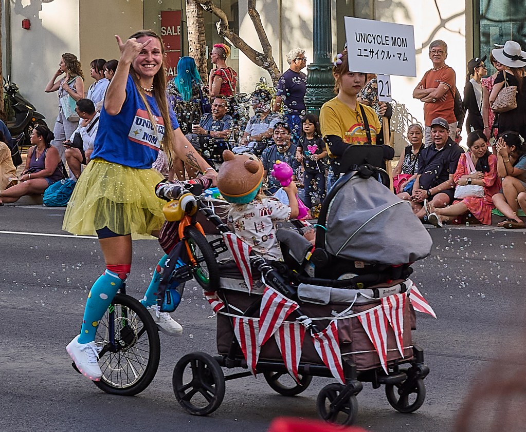 The Festival parade included a single unicyclist mom who pushed along her bubble blowing child in its decorated stroller. David Croxford/Civil Beat/2025