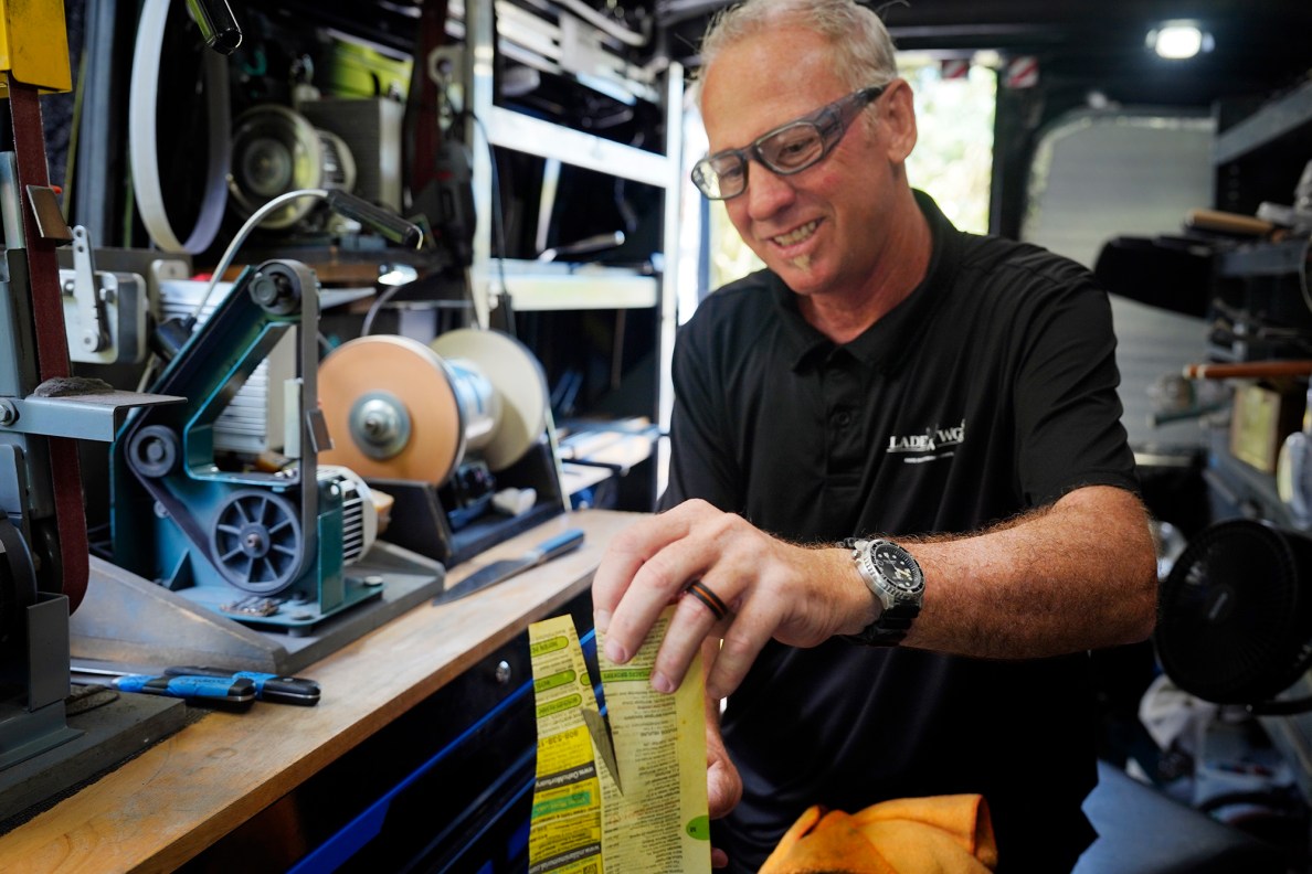 Blade Works 808’s Jeff Bonisa tests every knife he sharpens Wednesday, Aug. 25, 2025, in Kahuku. Bonisa uses old telephone book pages. (Kevin Fujii/Civil Beat/2025)