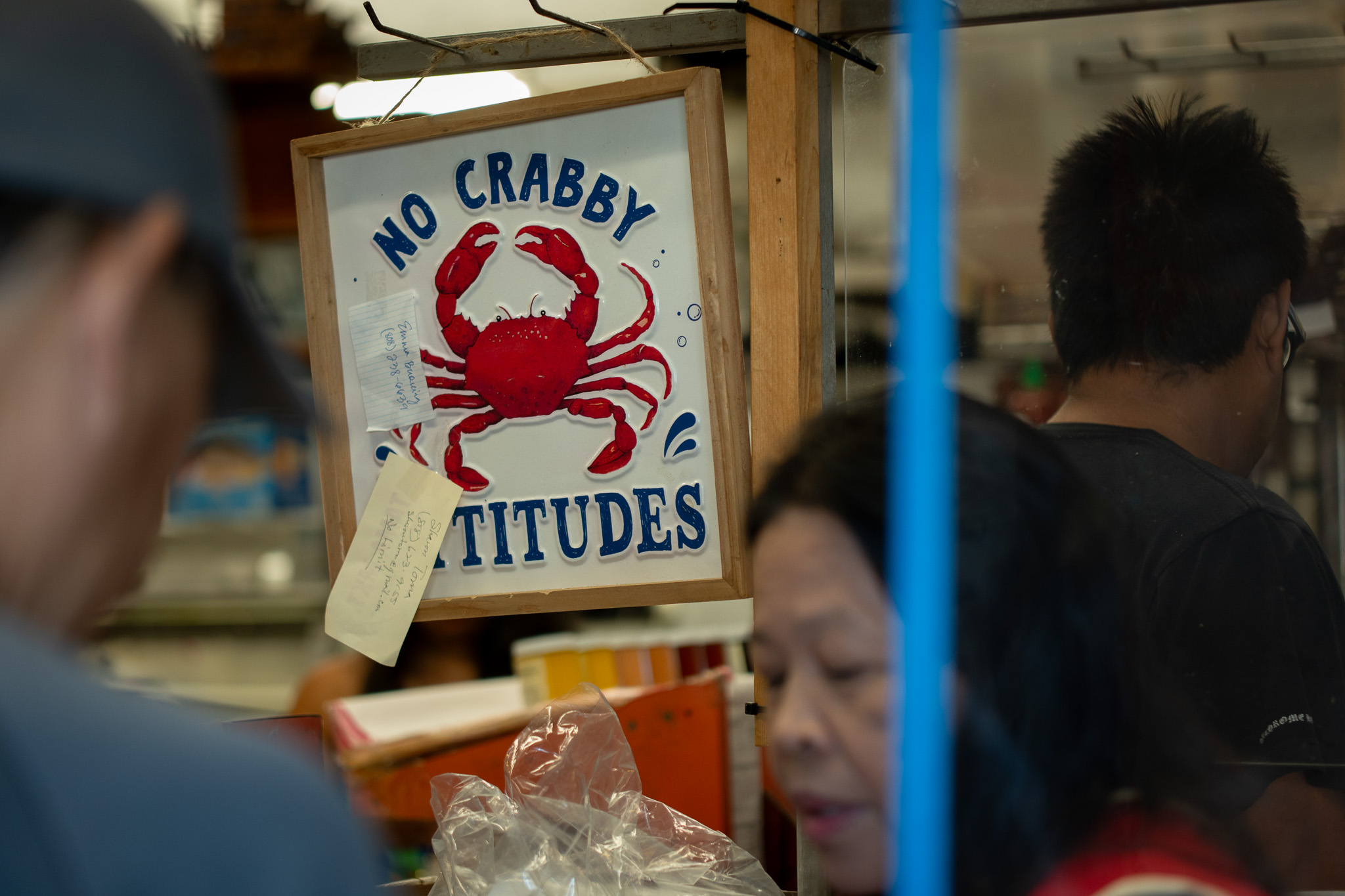 A sign to check one's attitude greets customers at Jenny Ancheta's register at Tamashiro Market April 3, 2026. Ancheta, at right, has been working at the market for almost 35 years. The market will close April 30th.