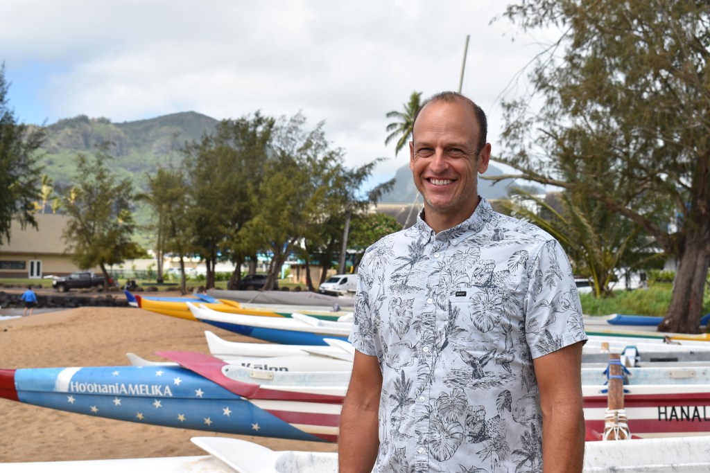 Luke Evslin, who is running for re-election, stands in front of a handful of canoes at Kalapakī Beach.