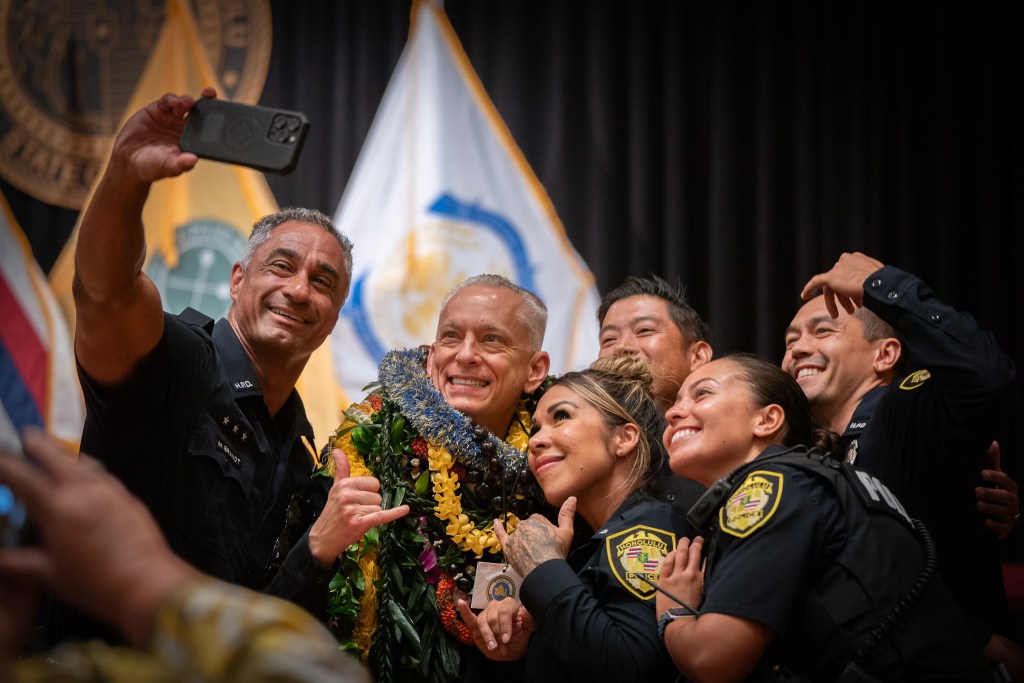 New HPD Chief David Lazar, with lei, poses for a selfie with officers after his swearing in ceremony at Memorial Auditorium in Honolulu July 2, 2026. (Craig Fujii/Civil Beat/2026)